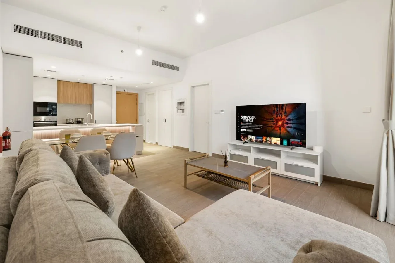 A bright living room with seating, a coffee table, and a television.