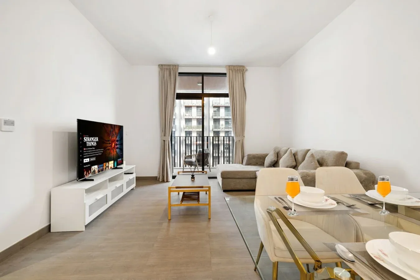 A bright living room with a television, seating, and a glass dining table.