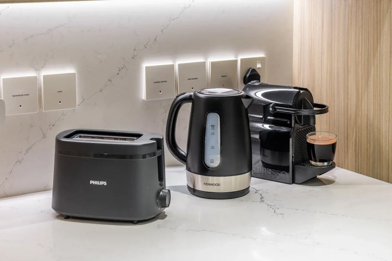 A kitchen counter displays a toaster, electric kettle, and coffee machine.