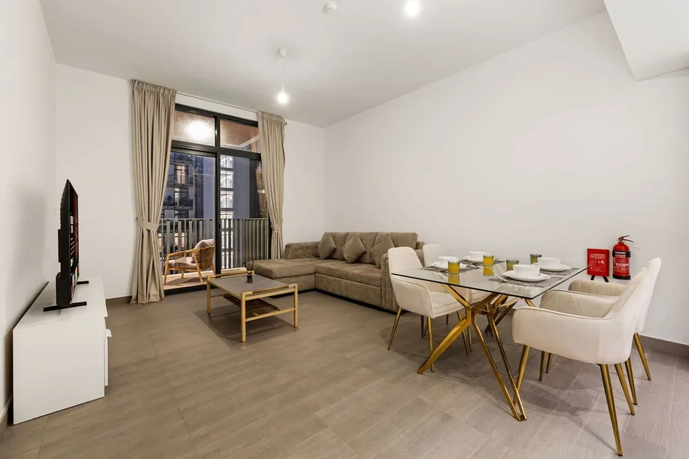 A living and dining area with seating, a table, and large curtained windows.