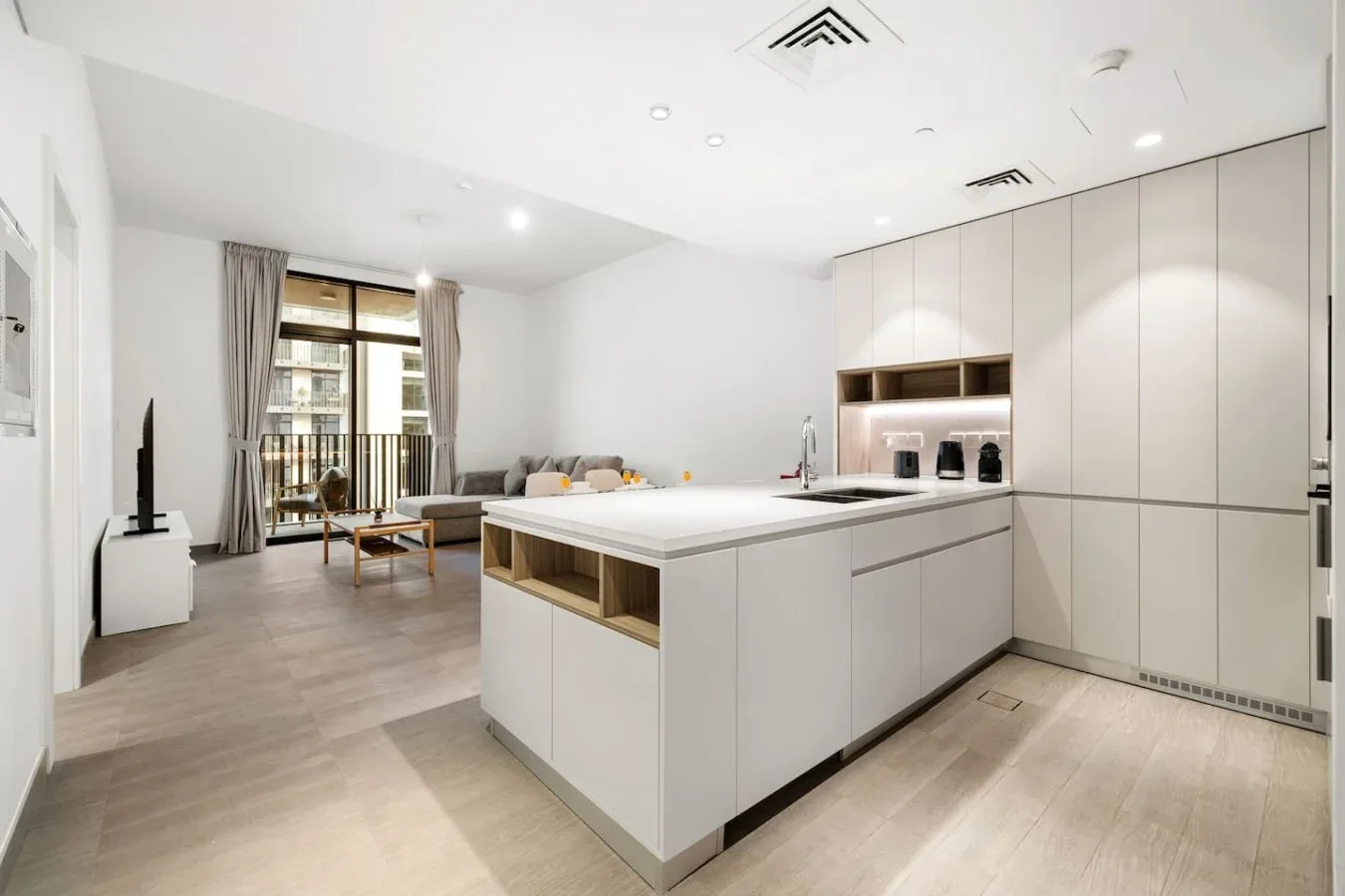A bright open-plan kitchen with a large island and living area beyond.