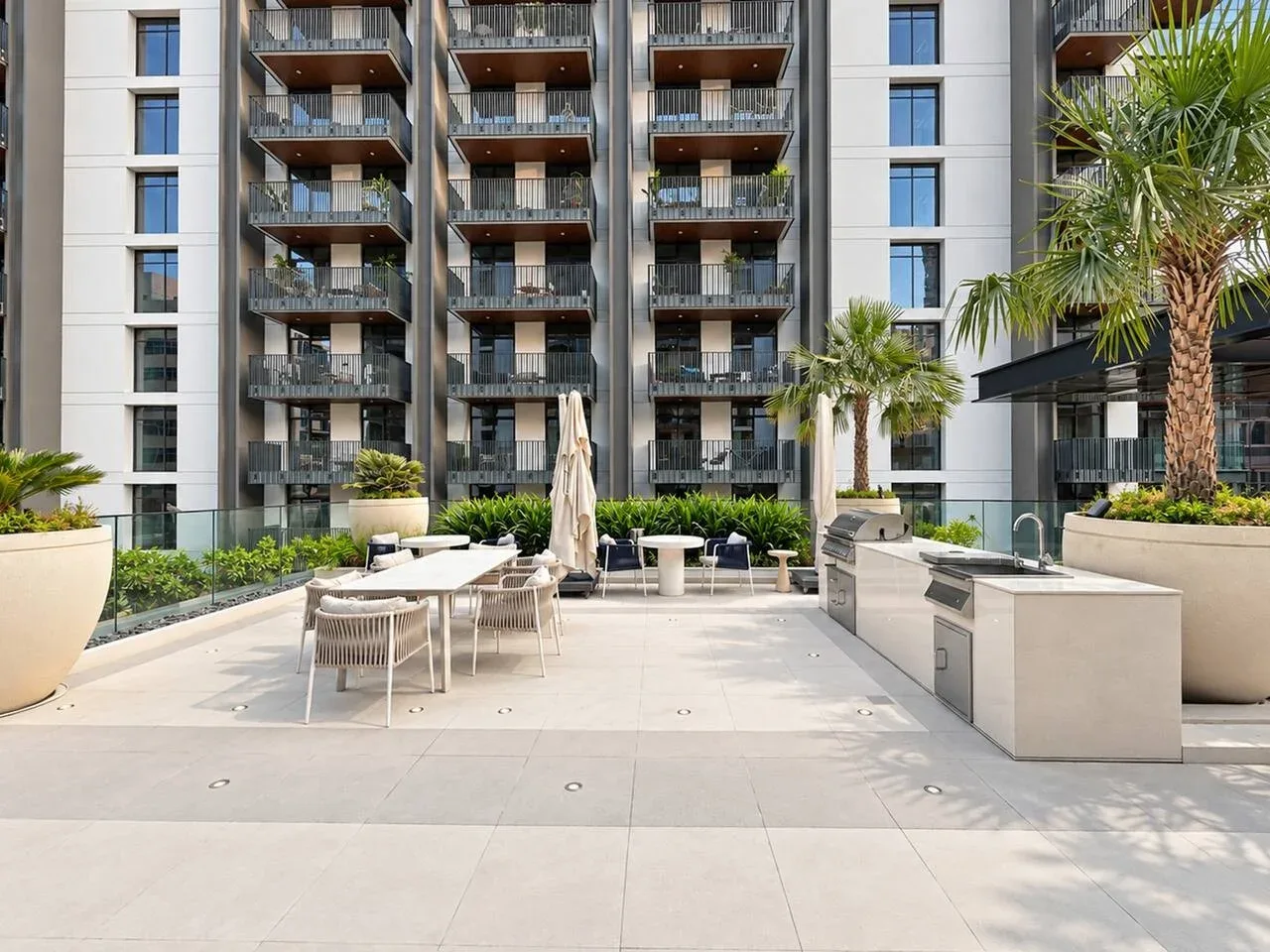 A paved outdoor terrace with seating and planters in front of a multistory building.