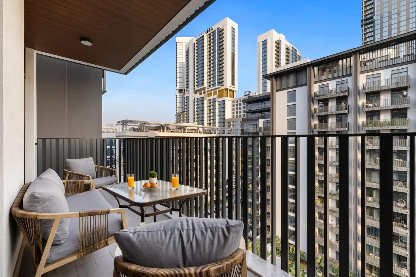 A furnished balcony overlooks several modern high-rise buildings.