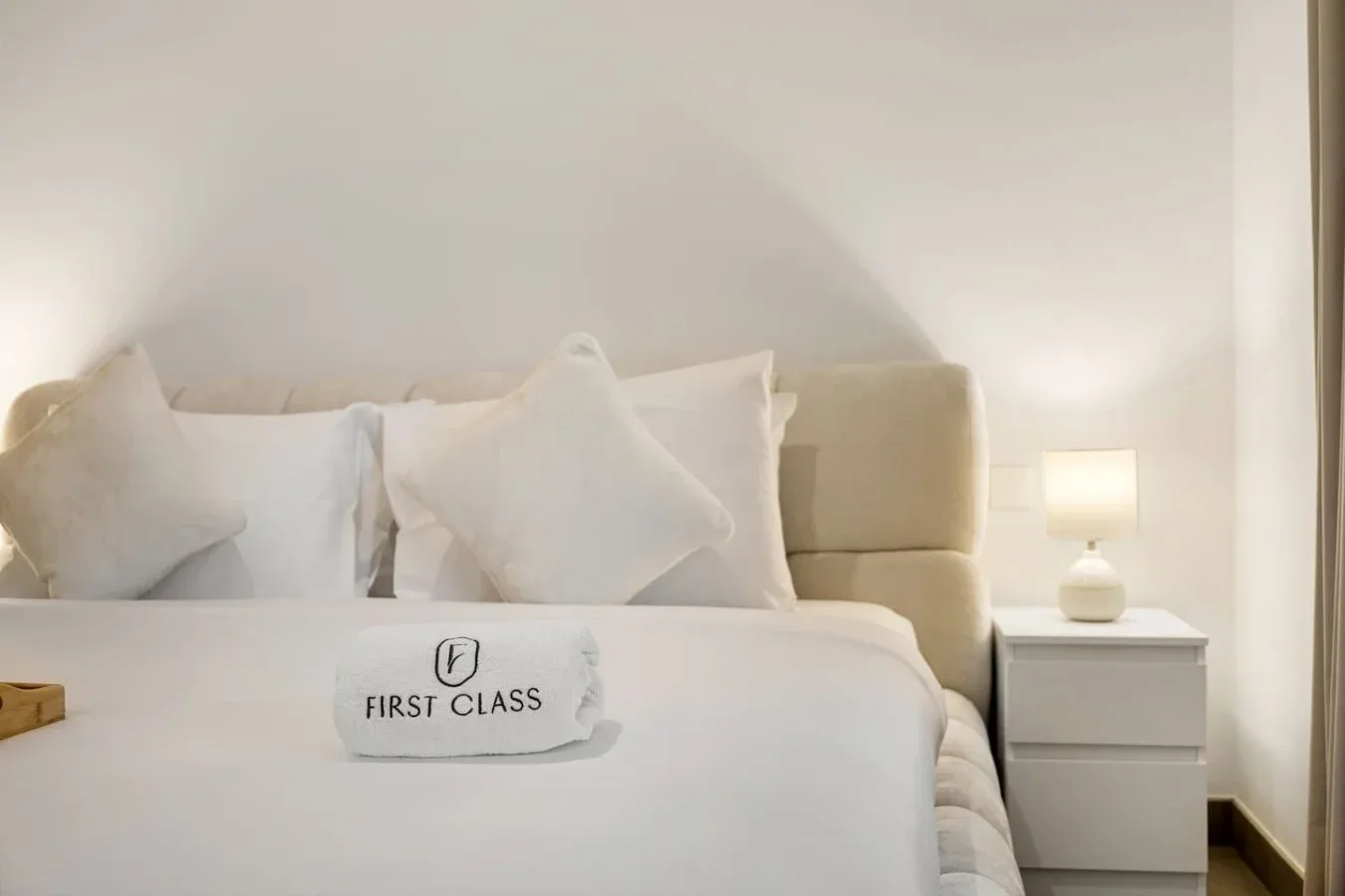 A bedroom with a neatly made bed and a lit bedside lamp.