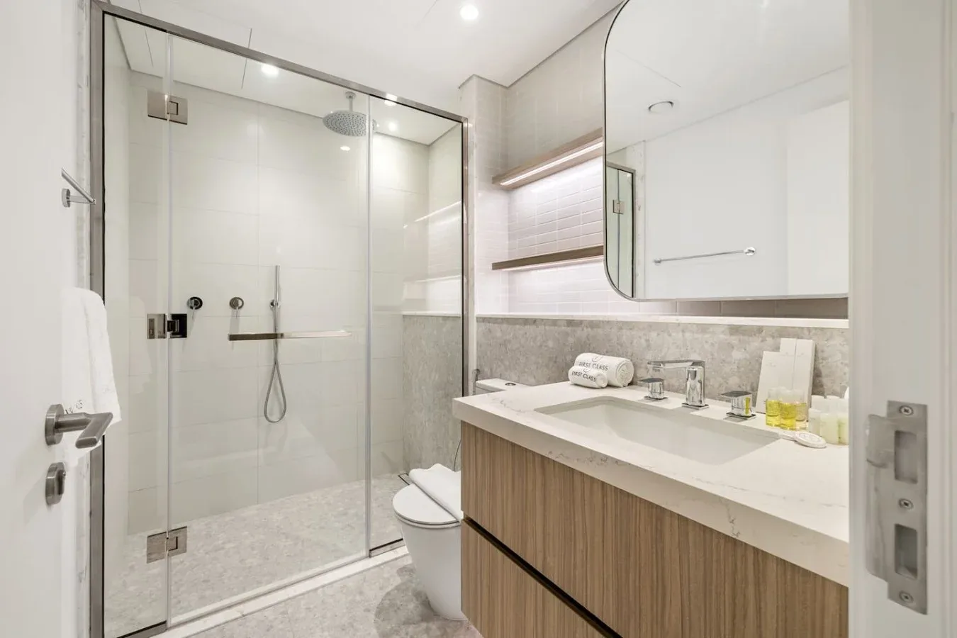A bright bathroom with a glass shower and a long vanity.