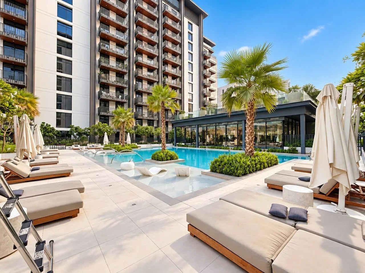 An outdoor swimming pool surrounded by lounge seating and apartment buildings.