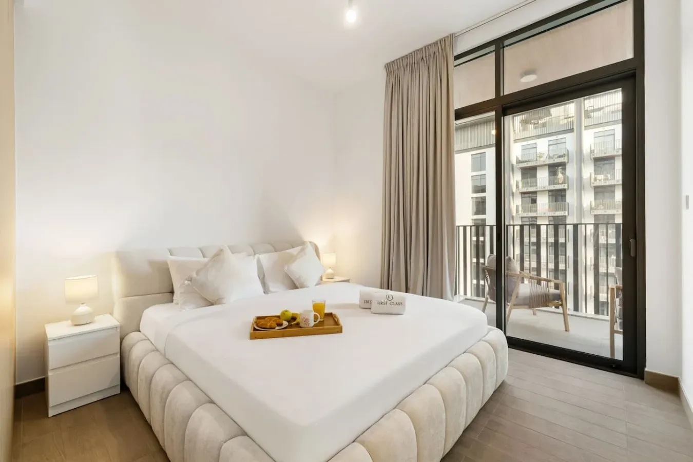 A bright bedroom with a neatly made bed and large windows.