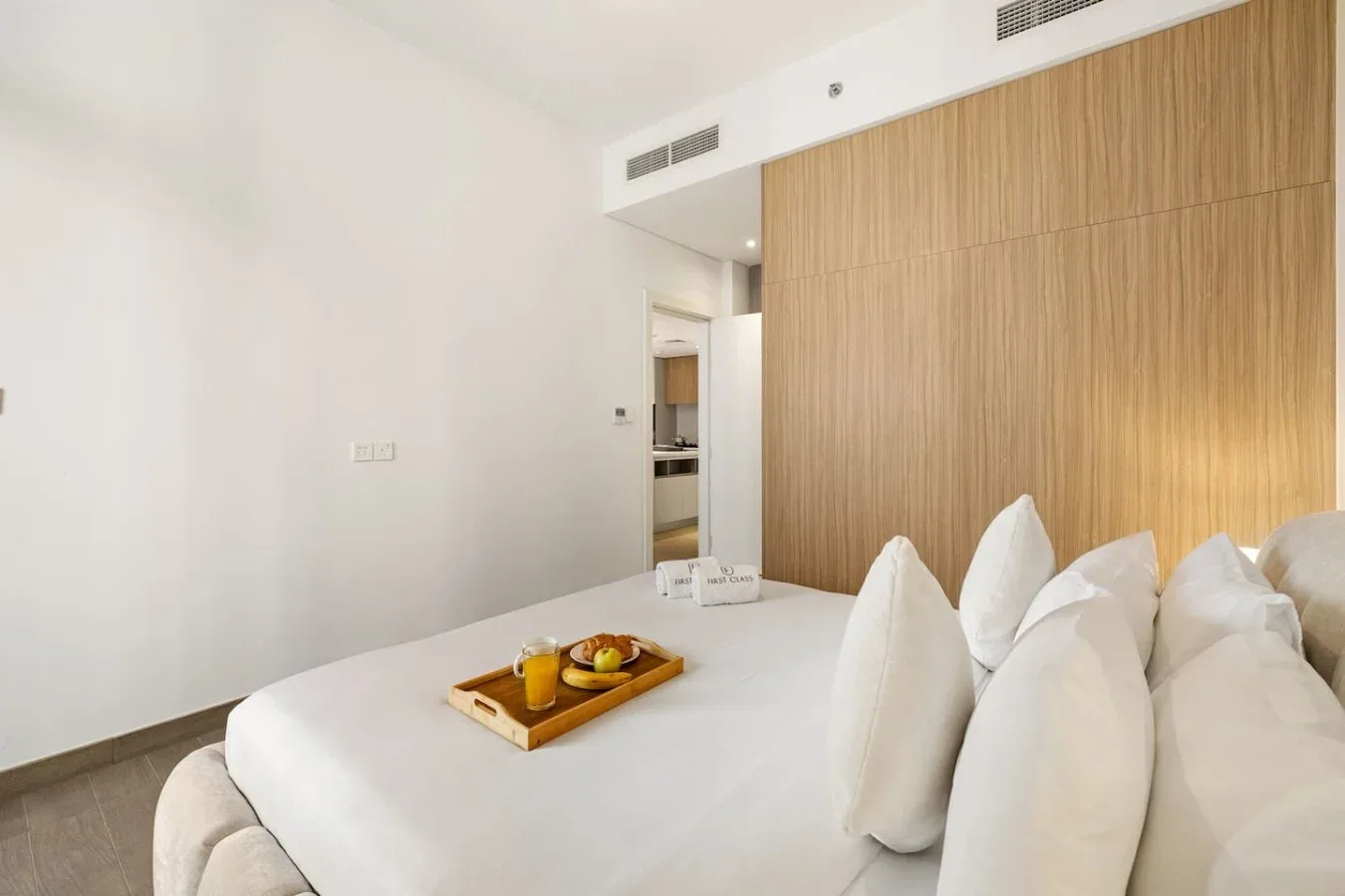A bedroom with a bed, white pillows, and a wooden wall panel.
