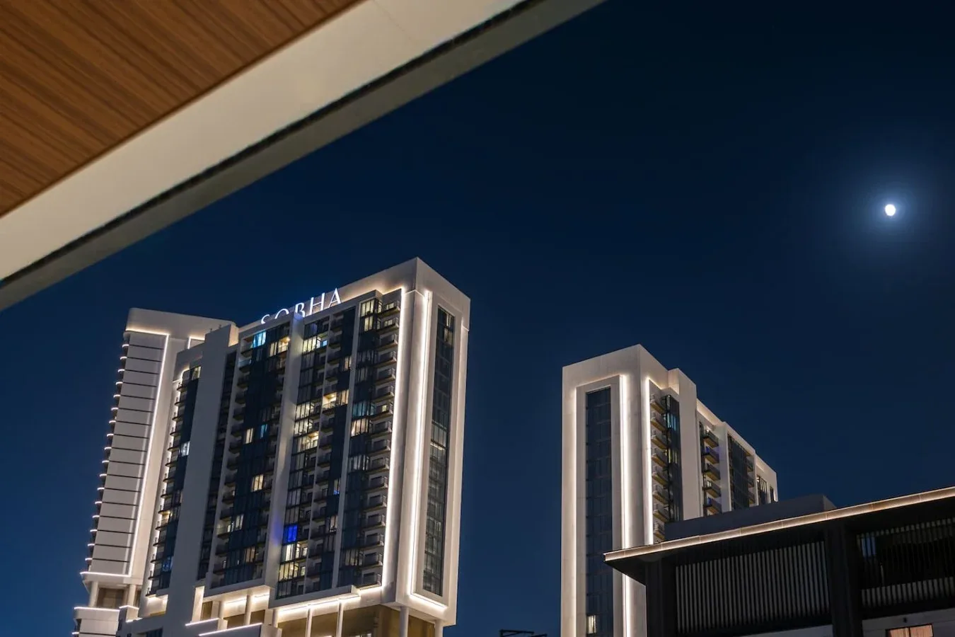 Nighttime city scene with illuminated high-rise buildings beneath a dark sky.