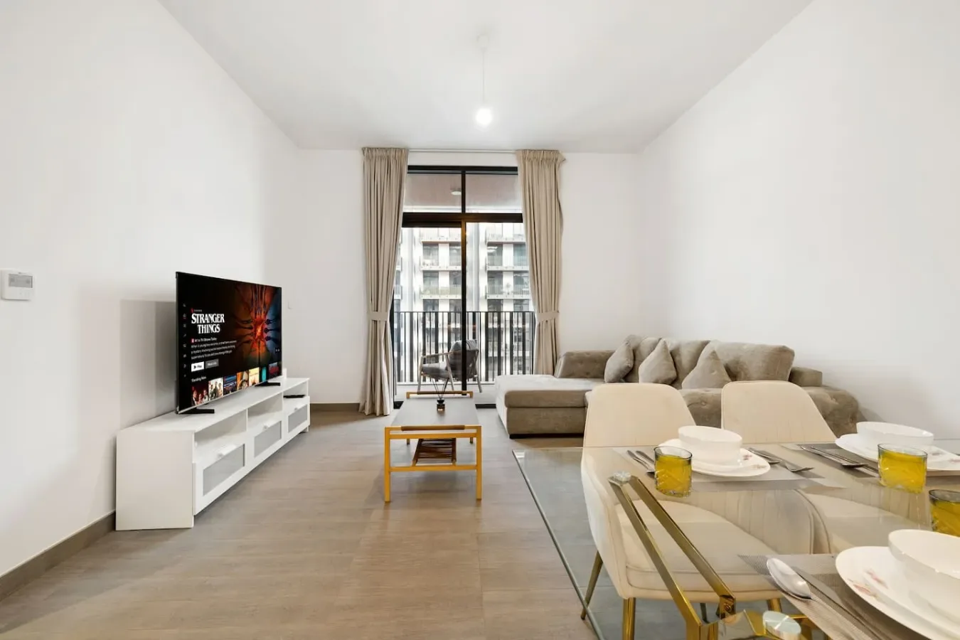 A bright living room with seating, a television, and a dining table by the window.