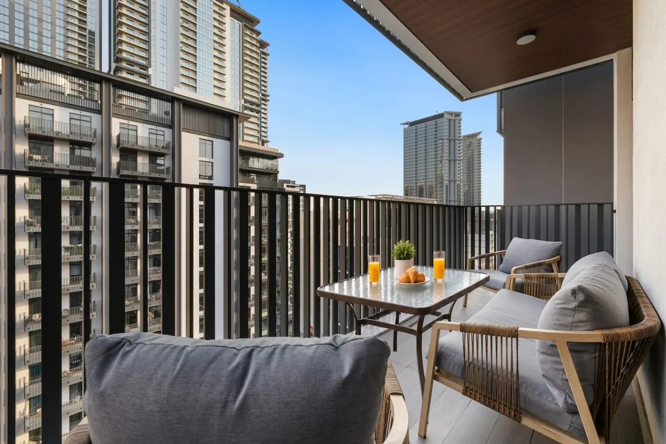 A balcony seating area overlooks nearby high-rise buildings.