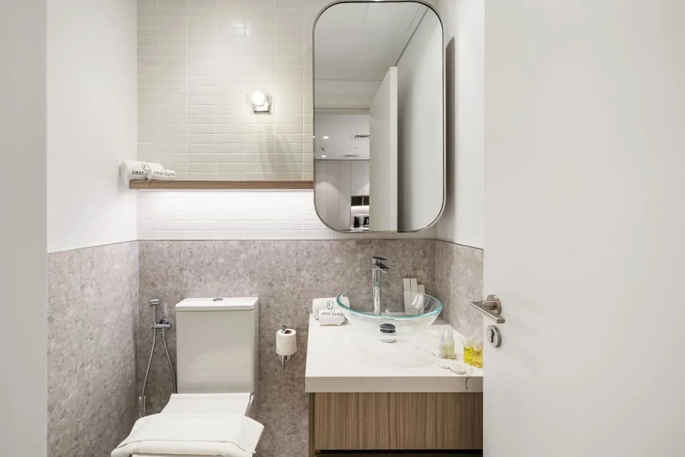 A bright bathroom with a sink, mirror, and tiled walls.
