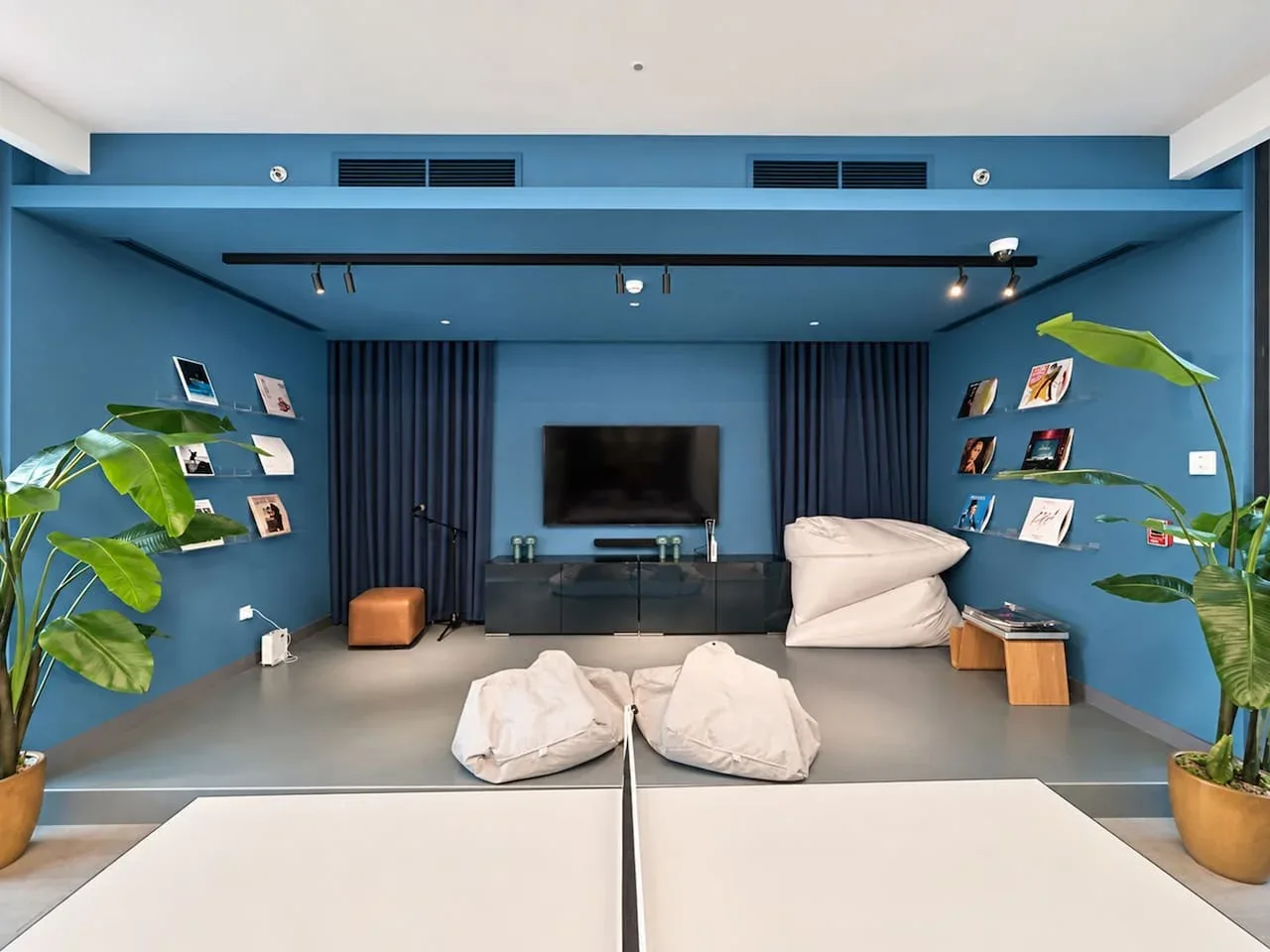 A blue media room with a wall-mounted television and casual seating.