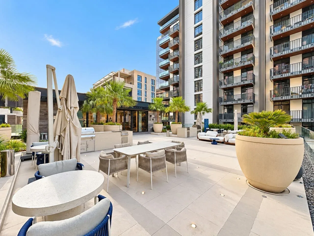 An outdoor residential patio with seating, tables, and potted plants.