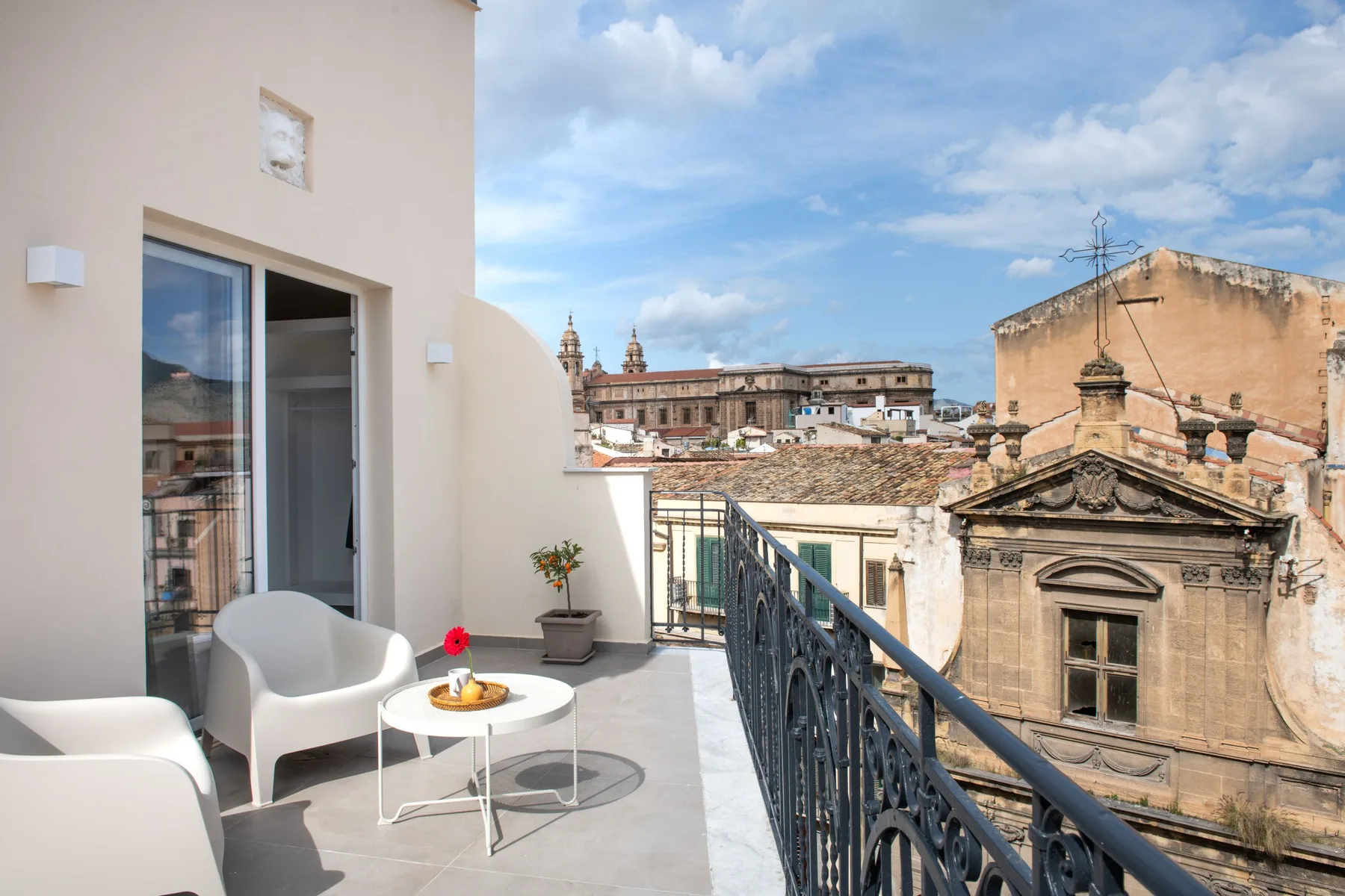 A rooftop terrace with seating overlooks historic buildings beneath a cloudy sky.