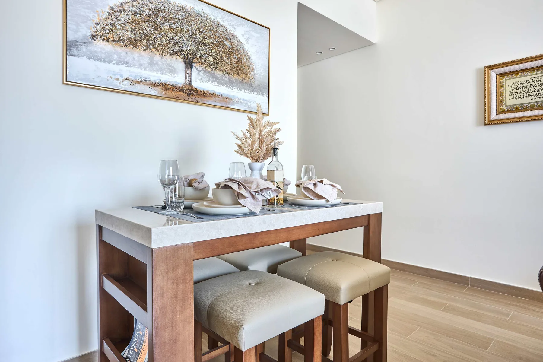 Comedor con la mesa puesta debajo de un cuadro enmarcado de un árbol.