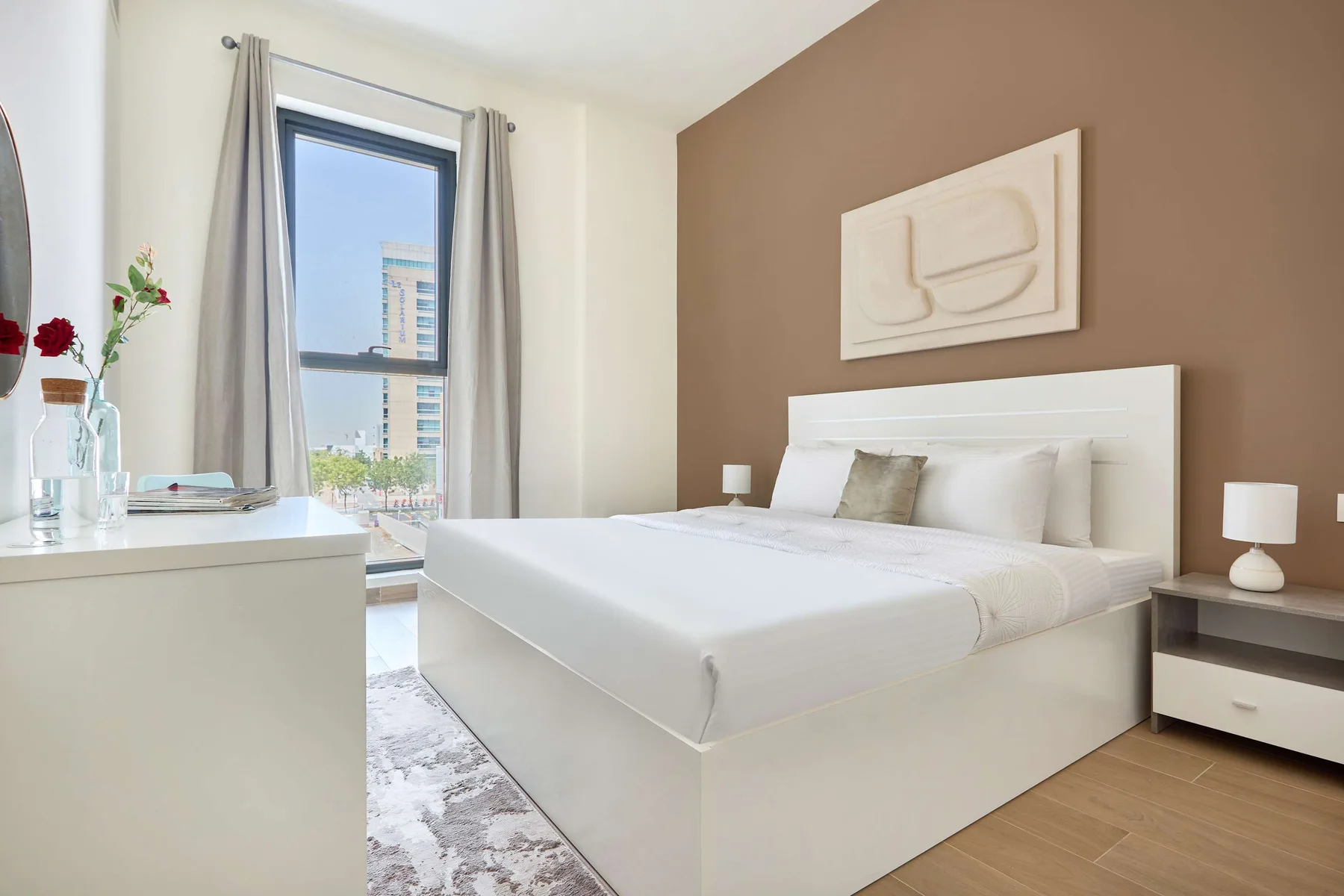 Un dormitorio luminoso con una cama bien tendida y una ventana alta.