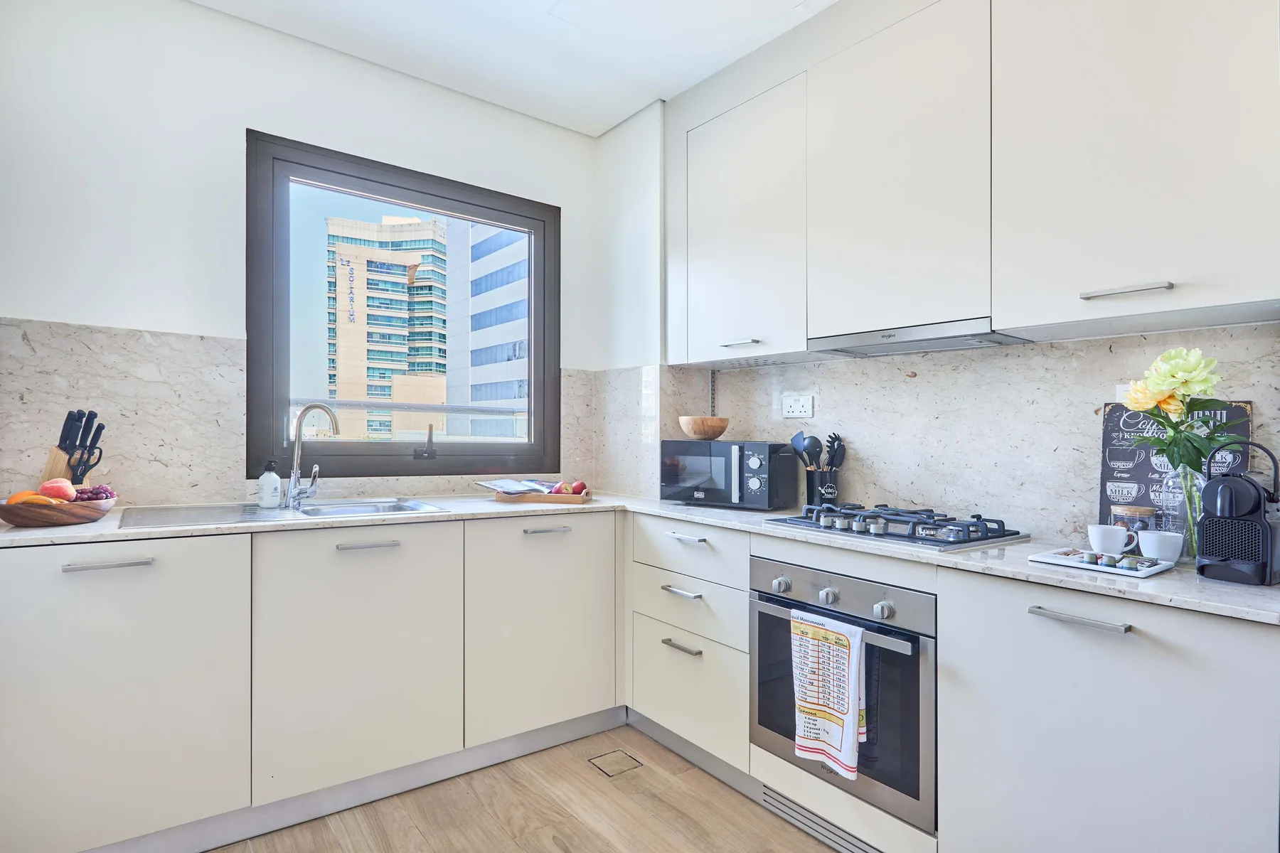 Una cocina luminosa con gabinetes blancos, una encimera y una ventana.