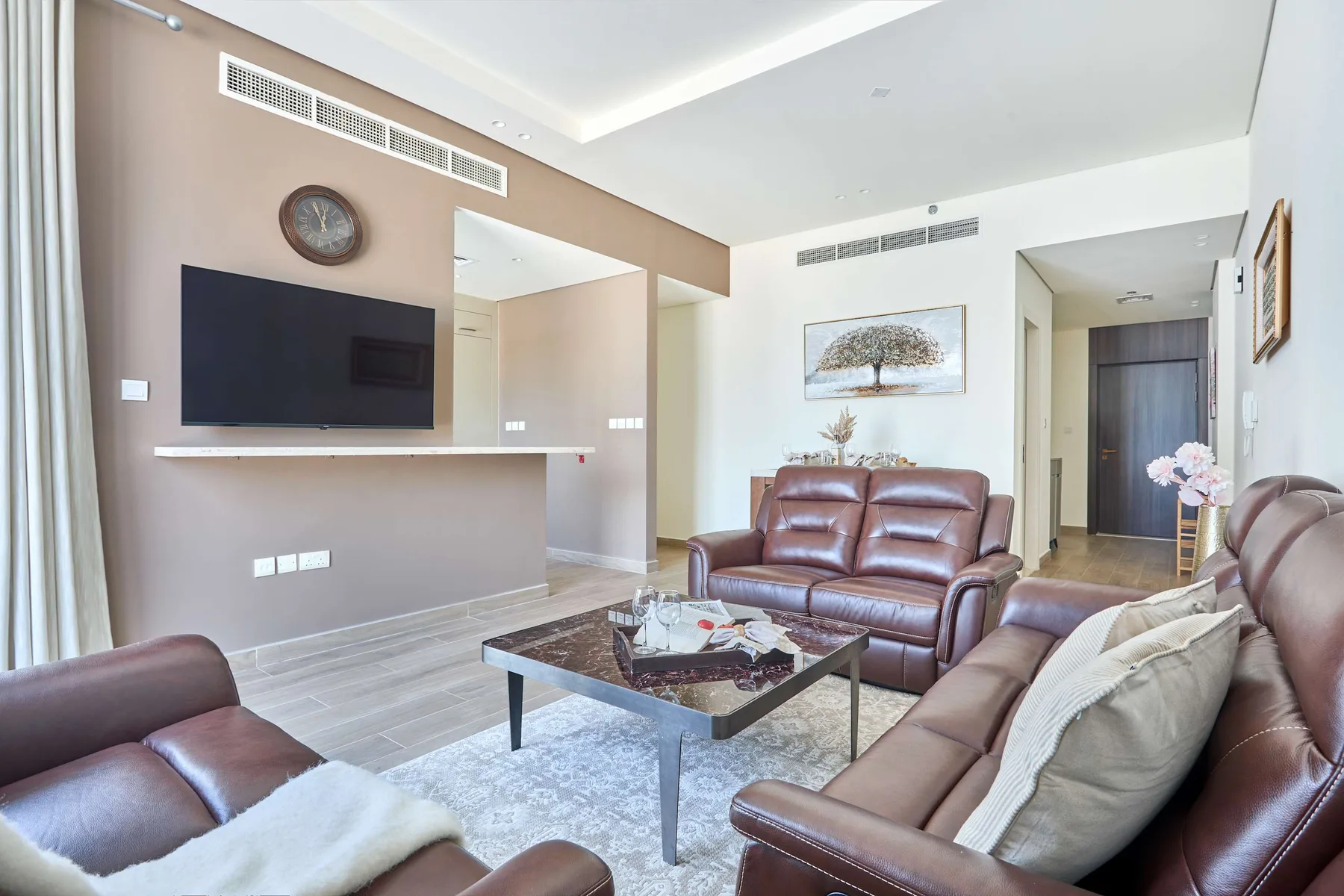 Una sala de estar con asientos marrones, un televisor y una mesa de centro.