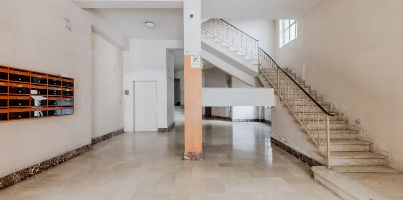 A bright interior hallway opens onto a staircase, with mailboxes along the wall.