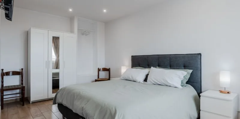 A bedroom with a large bed and a white wardrobe.
