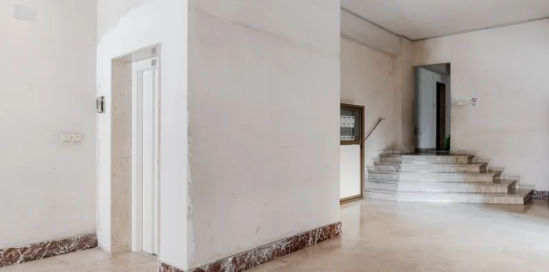 An interior hallway with a doorway and steps leading to a raised landing.