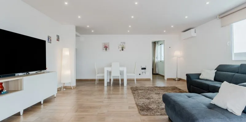 A bright living room with a dining table, television, and seating.