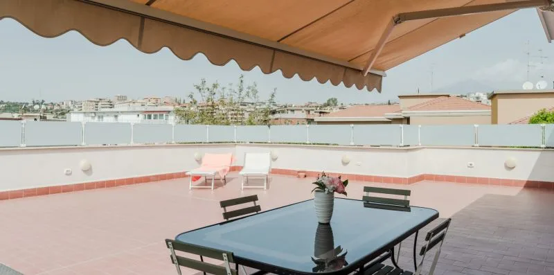 A rooftop terrace with an outdoor table and seating beneath a canopy.