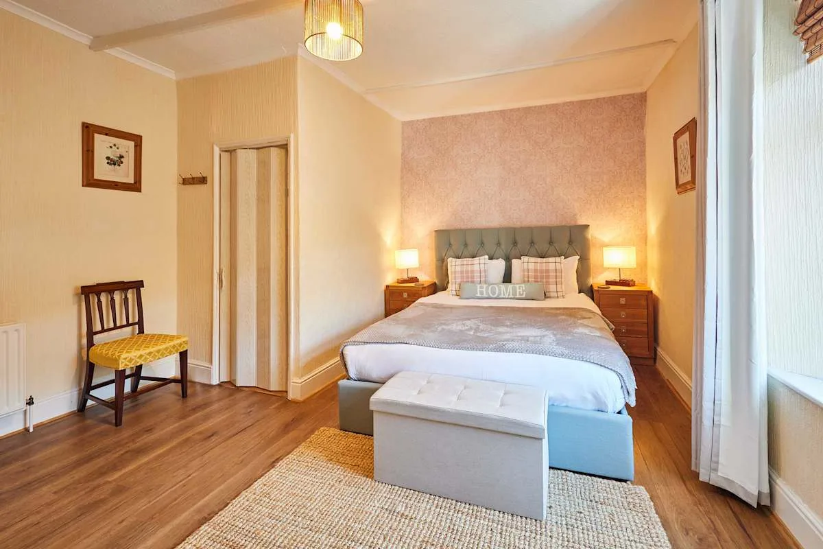A bedroom with a bed, bedside tables, and a light-colored bench.