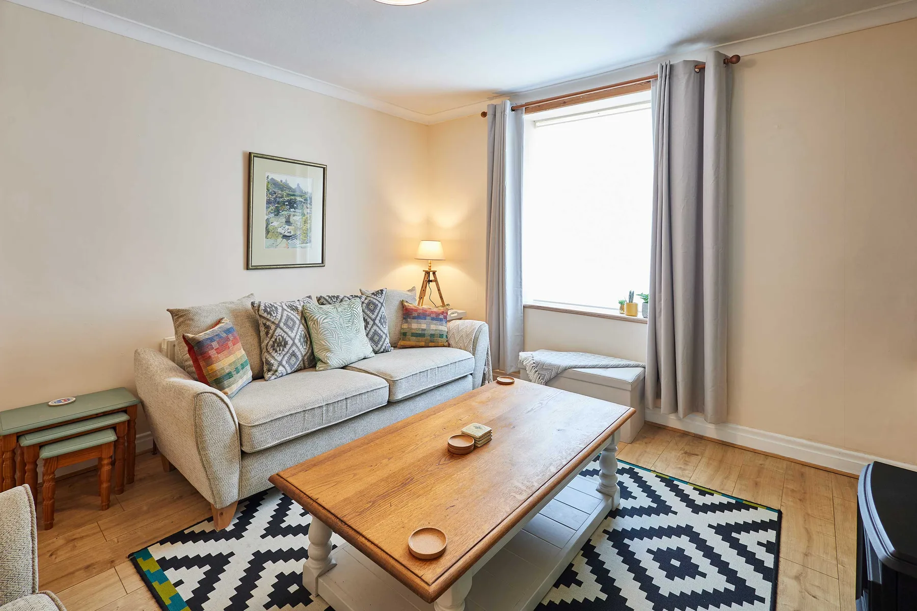 A bright living room with seating, a wooden coffee table, and a patterned rug.
