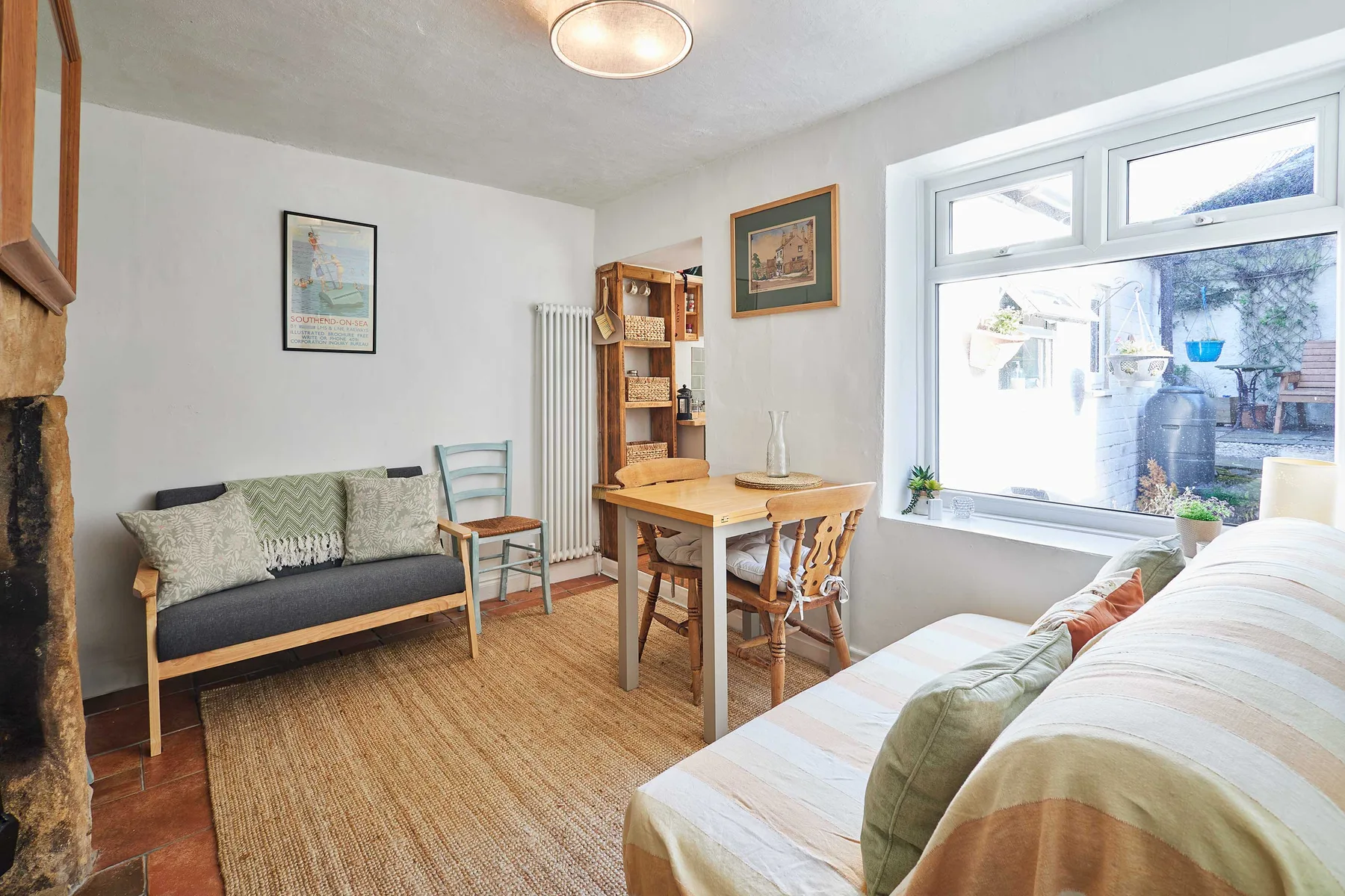A bright living room with seating, a dining table, and a large window.