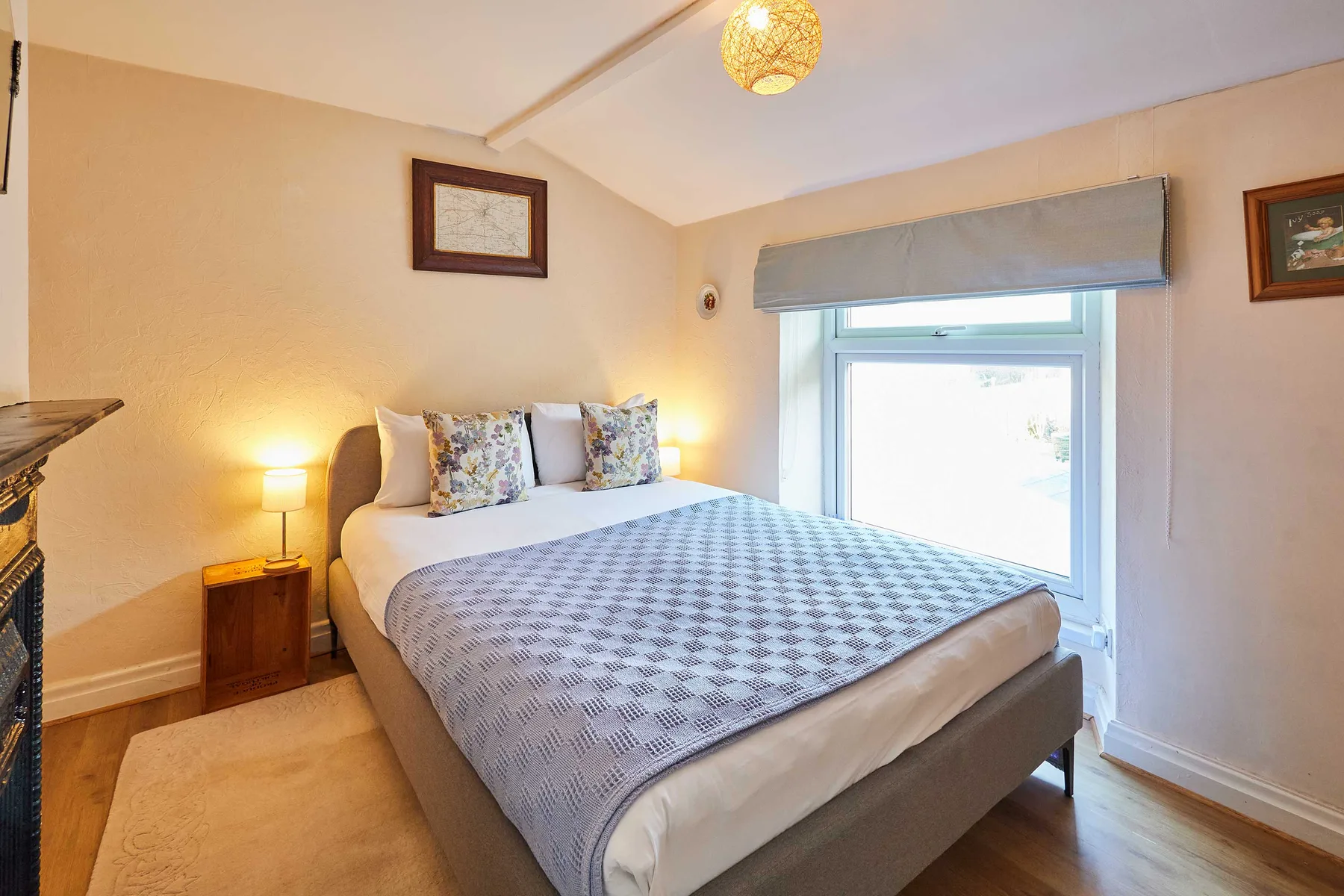 A bedroom with a double bed, patterned bedding, and a bright window.