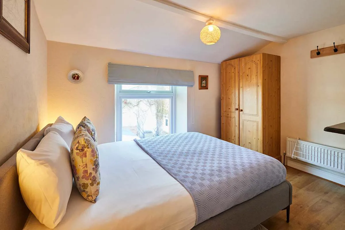 A bedroom with a bed, patterned cover, and wooden wardrobe.
