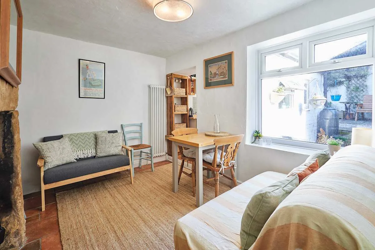 A bright living and dining area with seating, a table, and a large window.