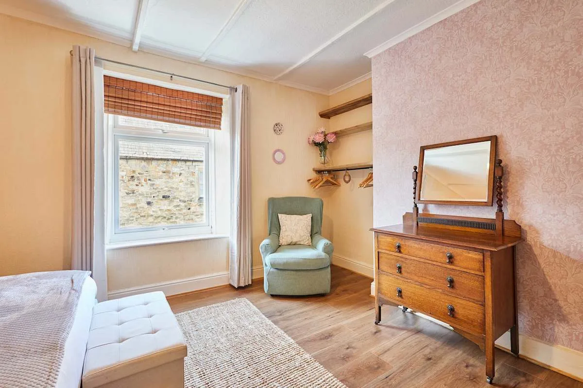 Bedroom with a window, armchair, and wooden dresser.