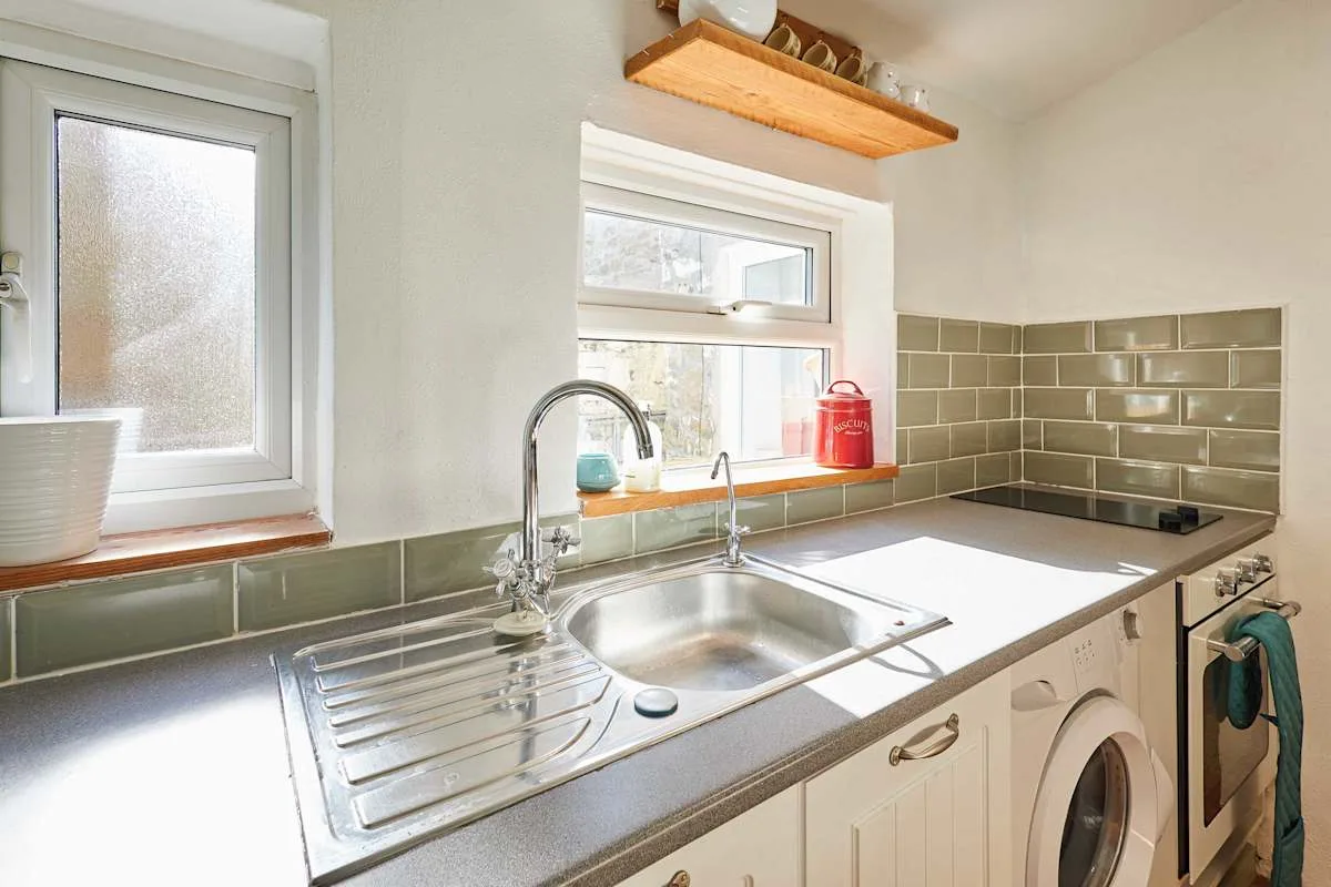A bright kitchen with a stainless-steel sink beneath the windows.