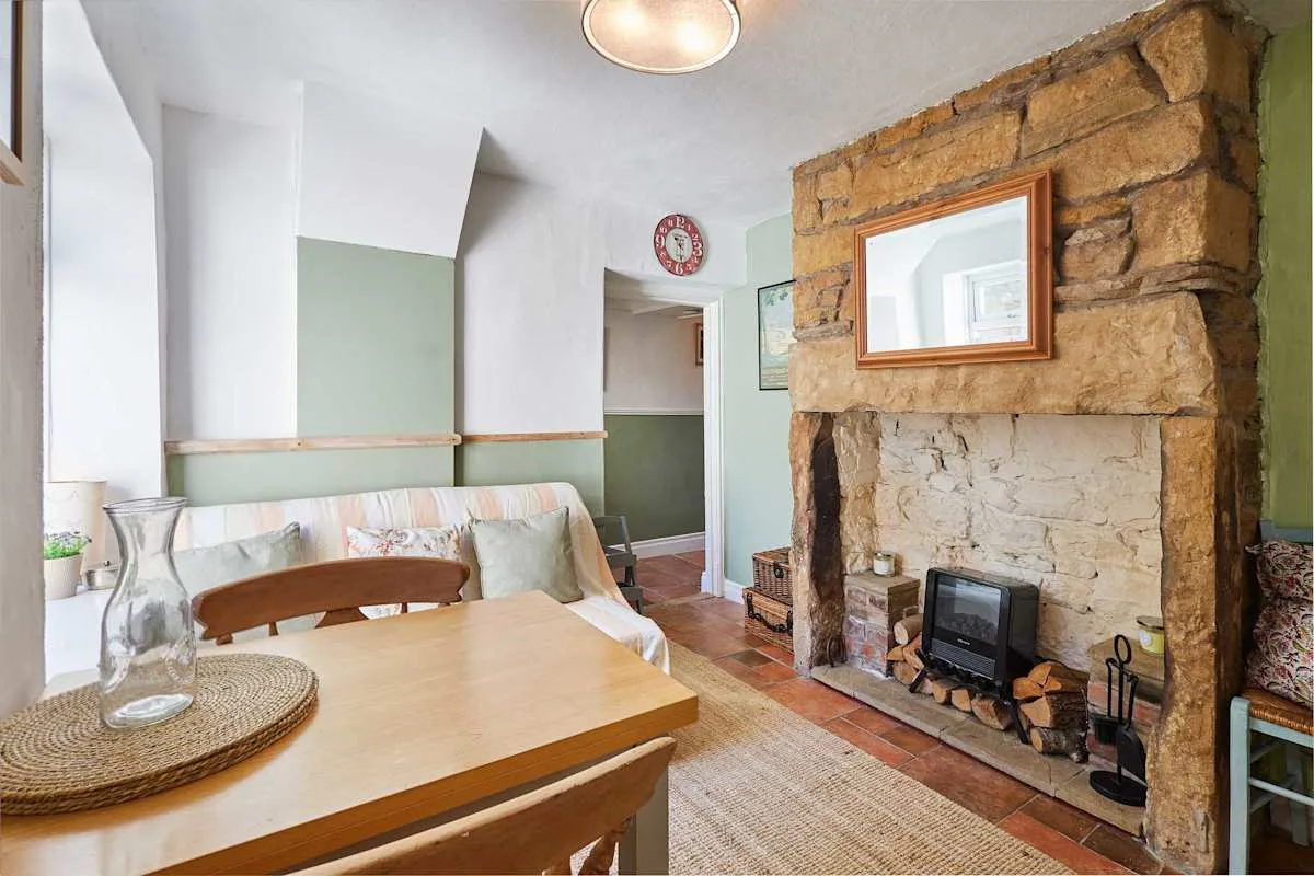 A dining area with a wooden table beside a large stone fireplace.