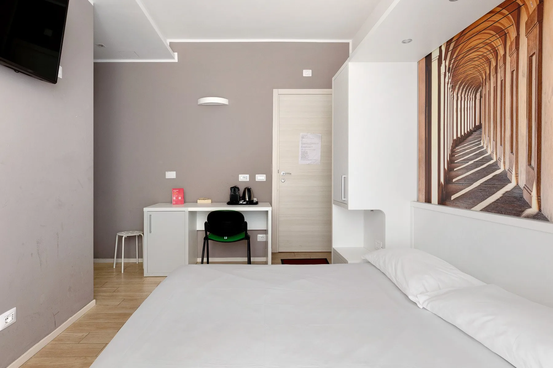 A bedroom with a bed, desk, and large wall mural.