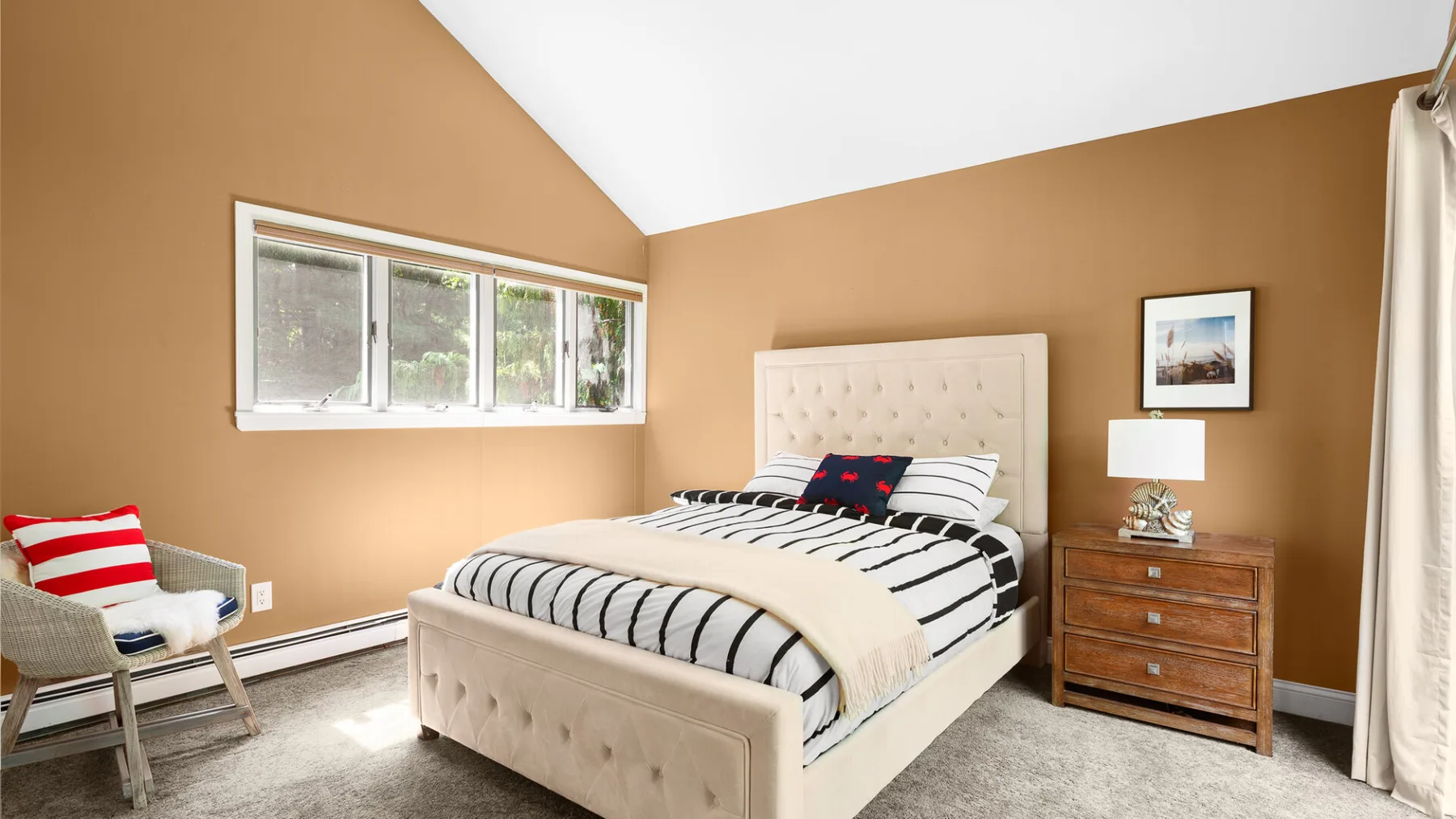 A bedroom with a striped bed and a window along the wall.