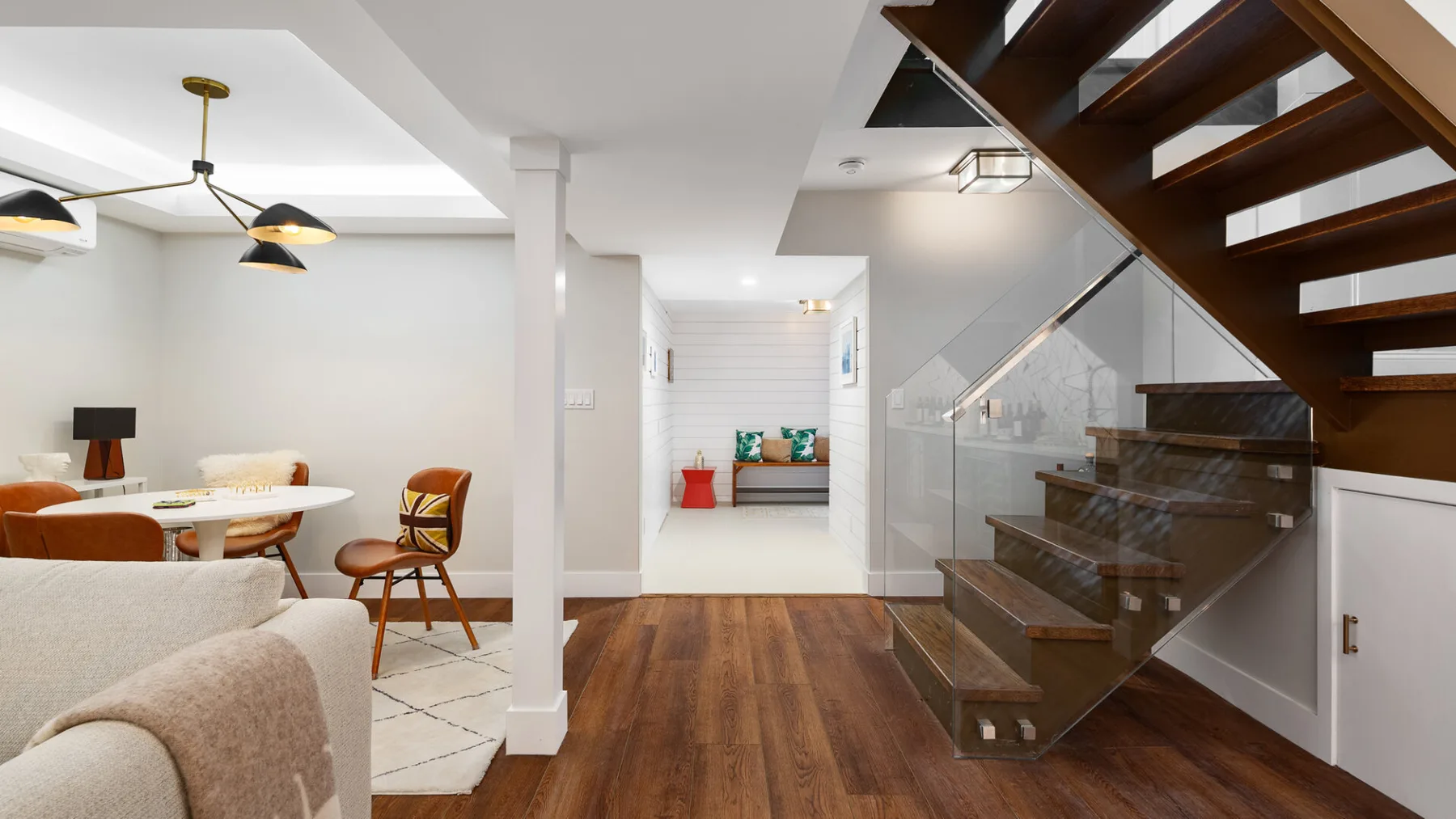 A bright open-plan living and dining area with a staircase and wood flooring.