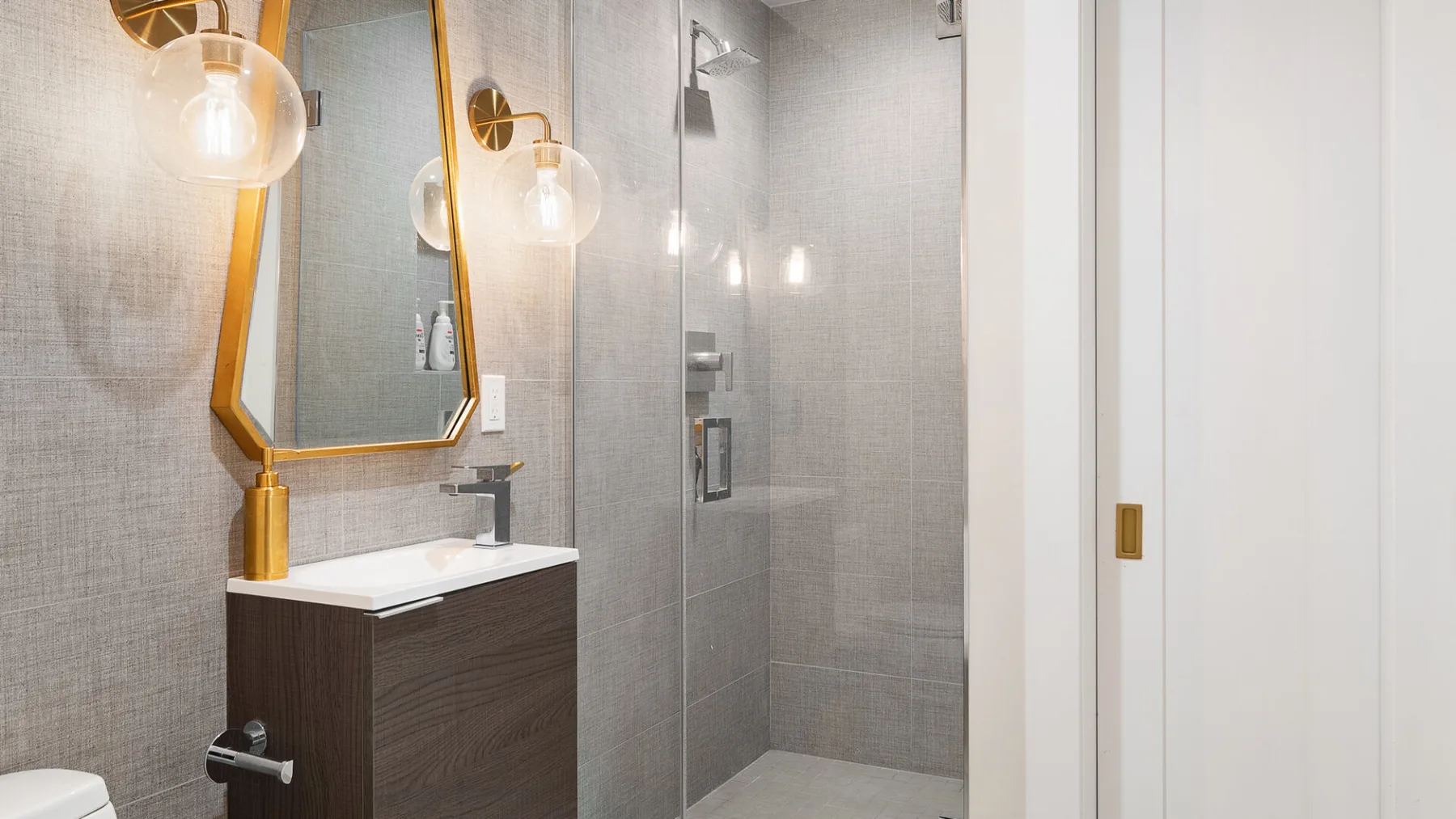 A modern bathroom with a vanity beside a glass-enclosed shower.
