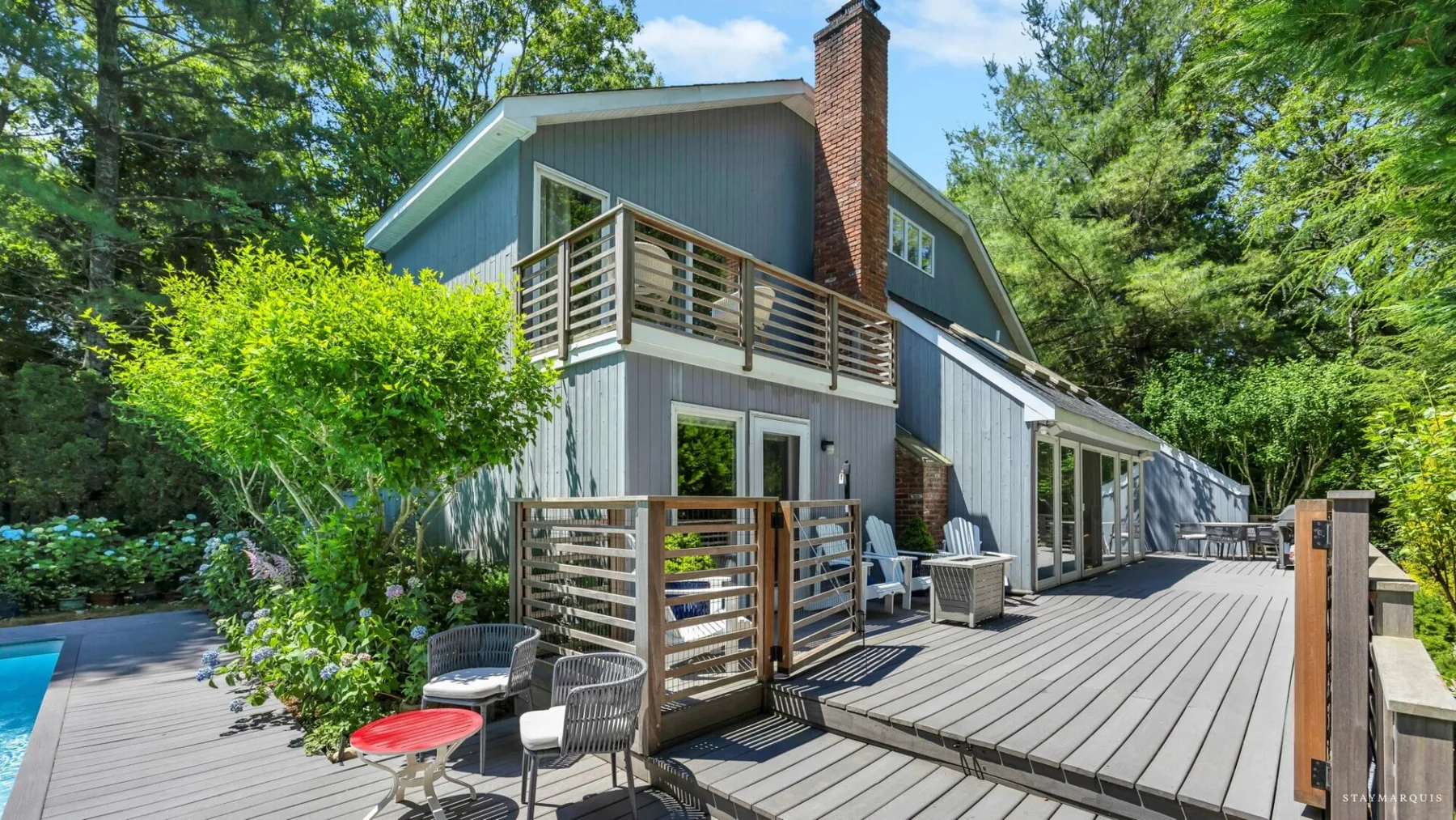 A wooded house with a spacious deck and outdoor seating.