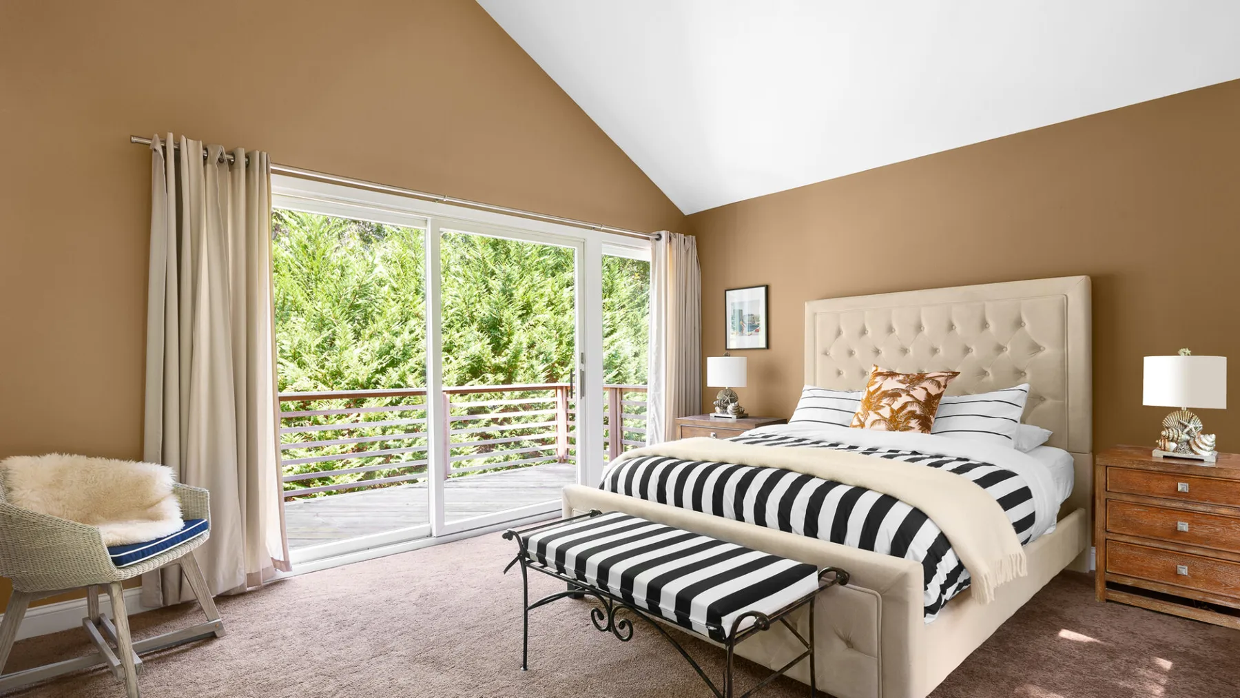 A bright bedroom with a large bed and wide windows overlooking greenery.