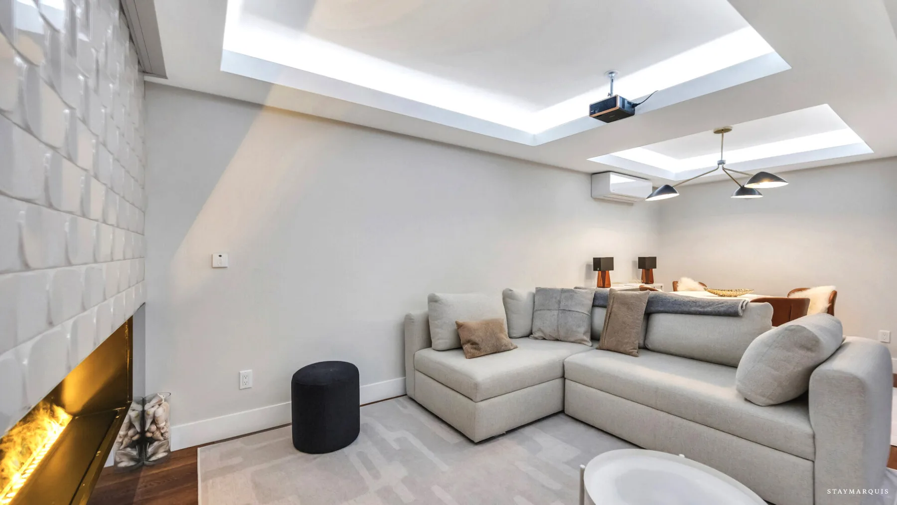 A modern living room with sectional seating beside a glowing fireplace.