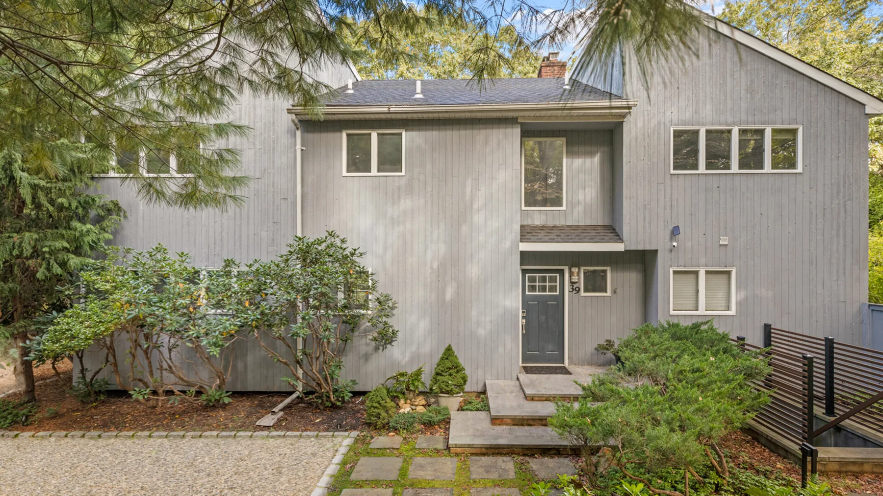 A gray house exterior with a front entrance and landscaped gravel yard.
