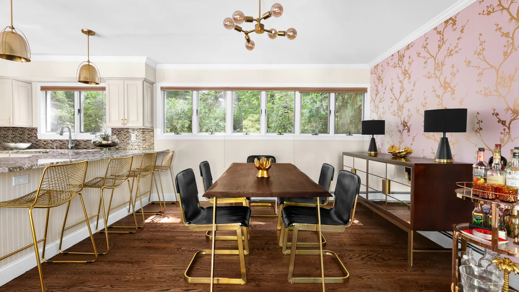 A dining area with a long table, bar seating, and large windows.