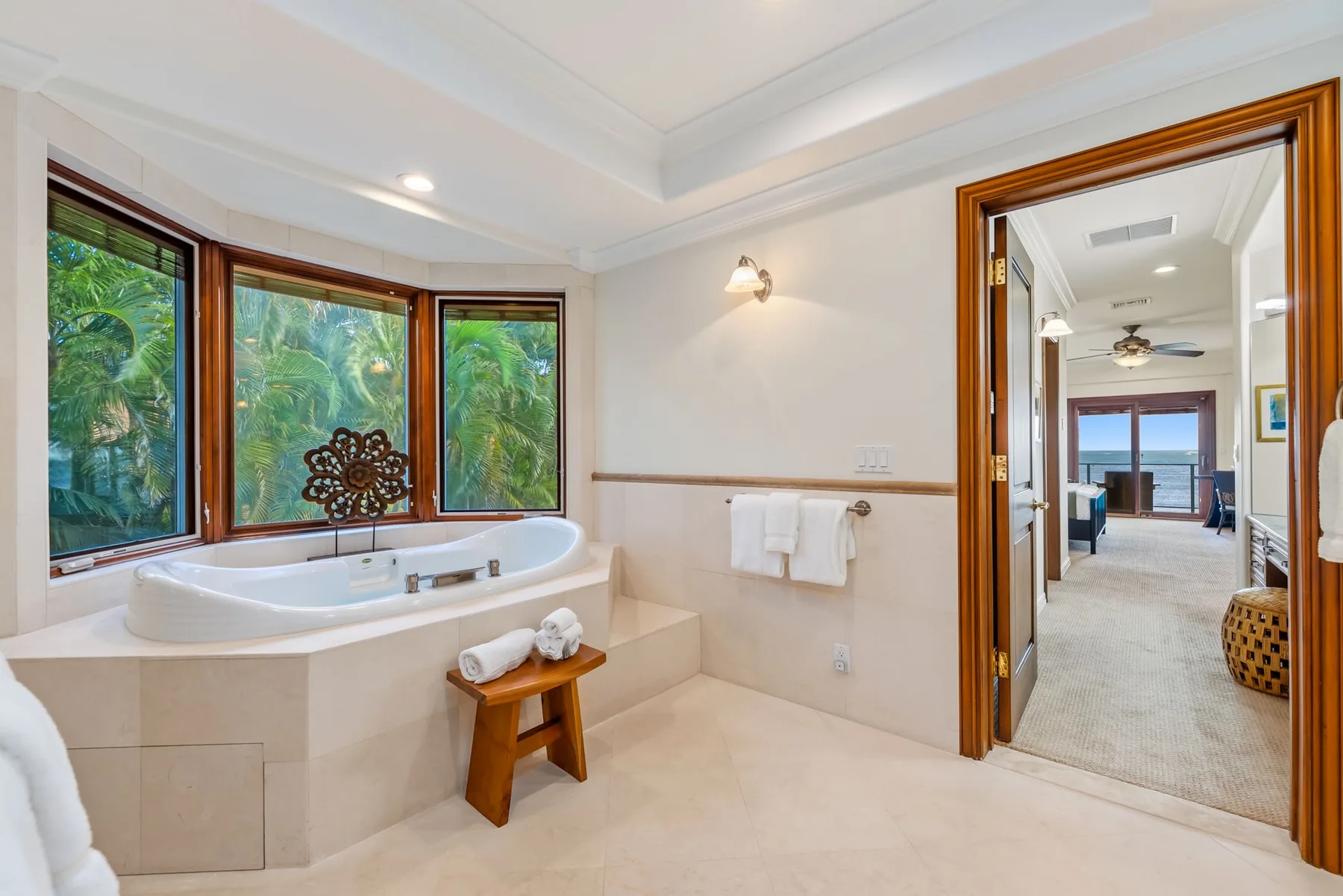 Un baño luminoso cuenta con una bañera empotrada bajo grandes ventanas con vistas a la vegetación.