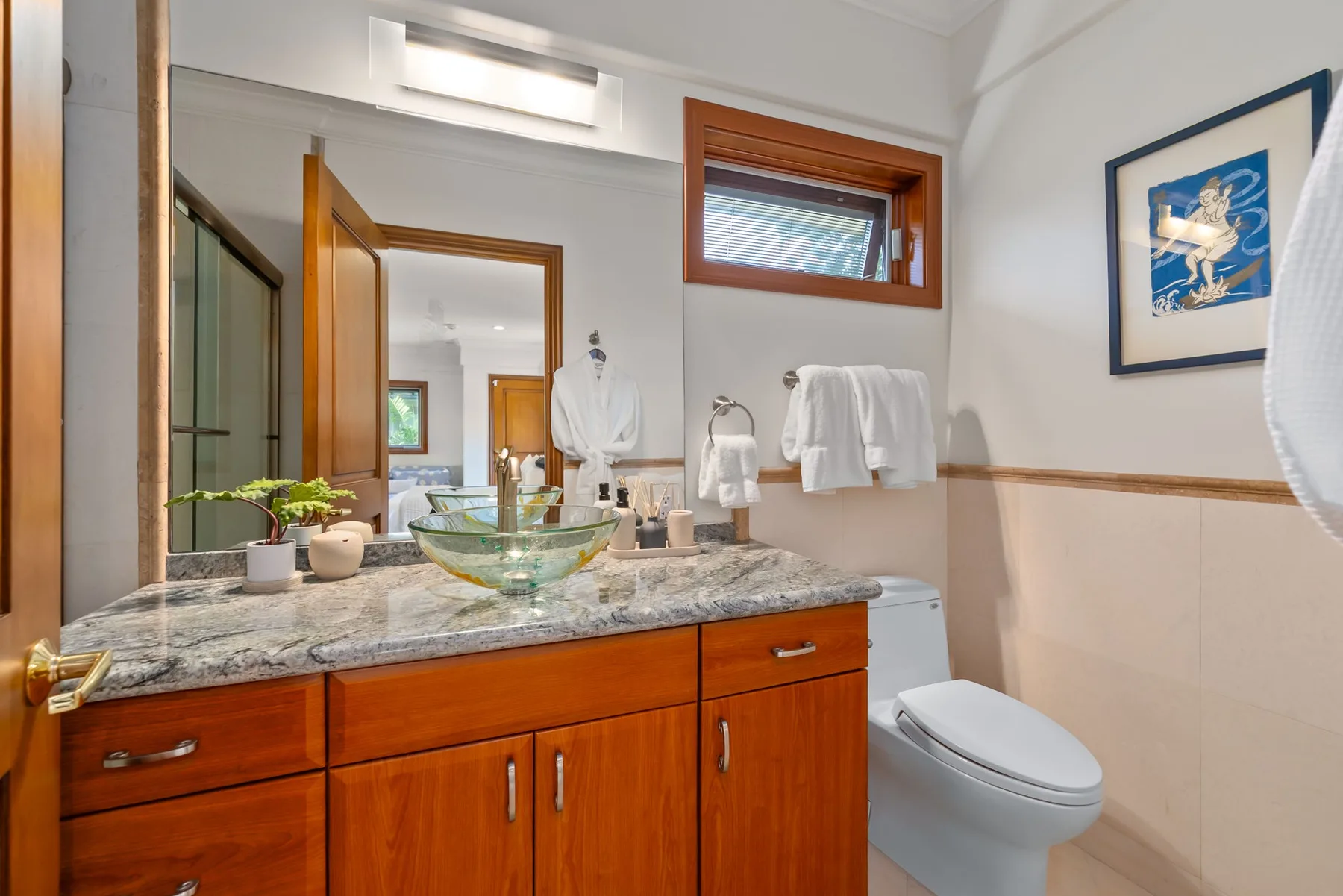 Un baño con un tocador de madera, lavabo e inodoro.