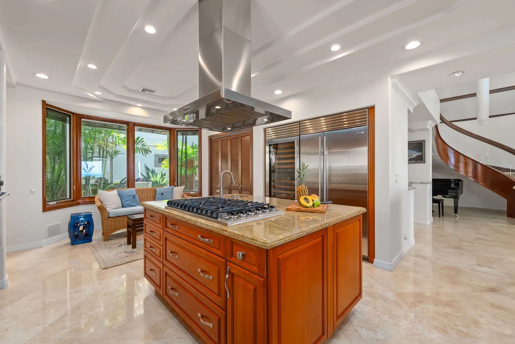 Una cocina luminosa tiene una isla central con una placa de cocina y ventanas alrededor.