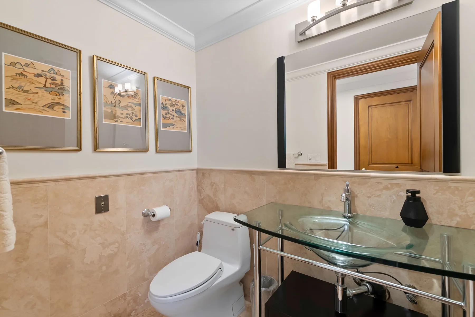 Un baño con inodoro, lavabo y un gran espejo de pared.
